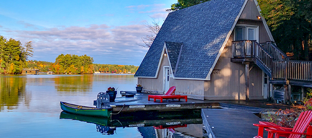A-frame cottage by the water with a motorized boat