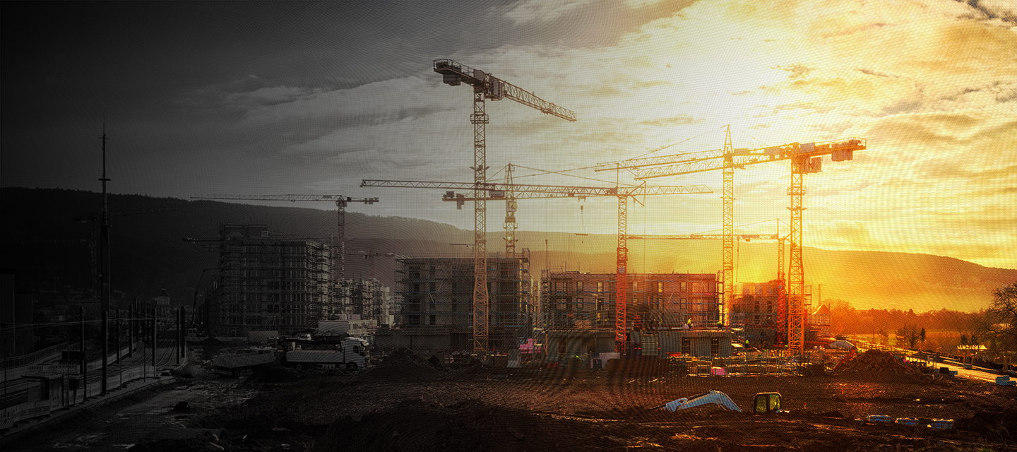 Large construction site including several cranes, with lots of gold sunlight